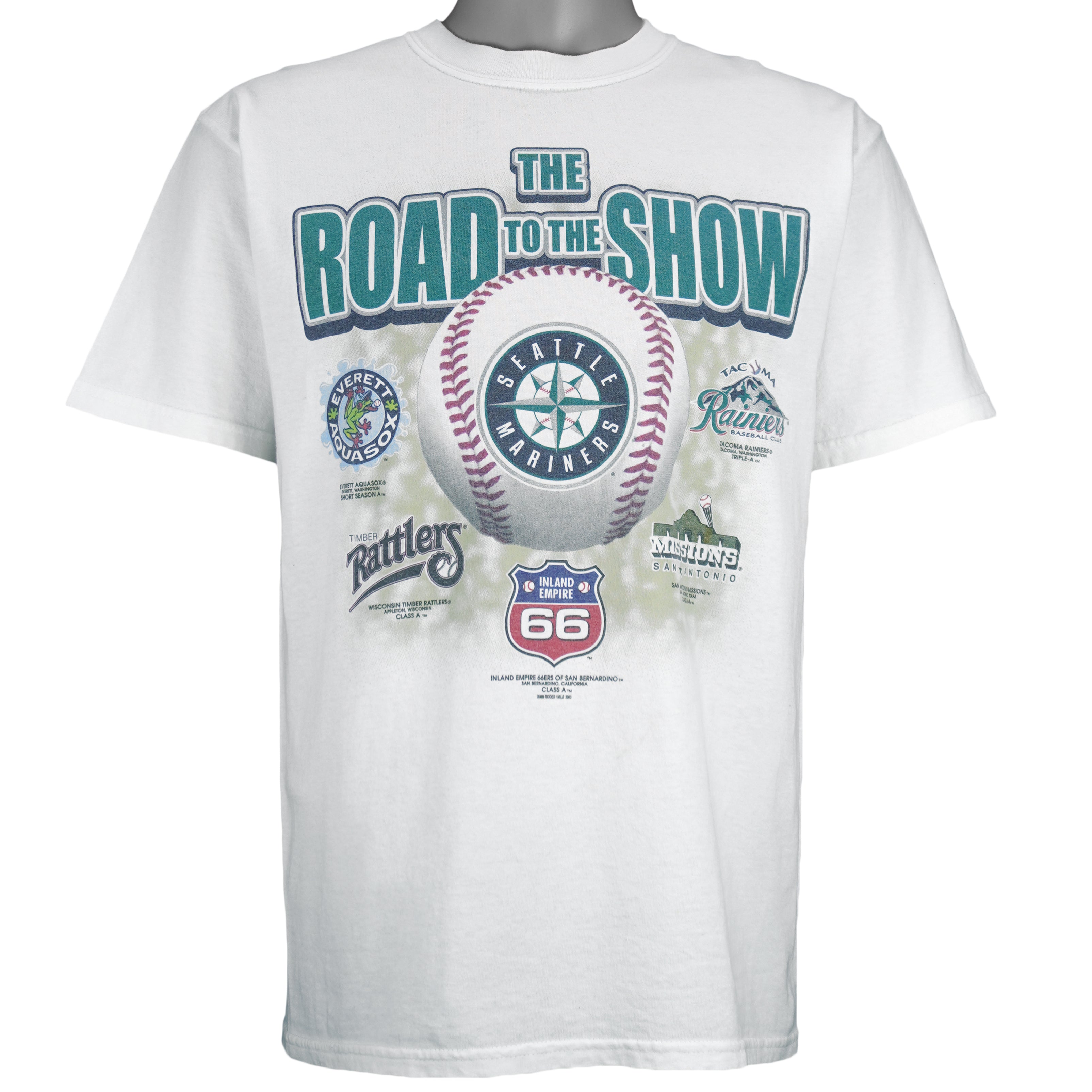 2003 vintage MLB Seattle Mariners "Road to the Show" spell-out T-Shirt by Gildan. White in color with farm team logos (Everett Aquasox, Wisconsin Timber Rattlers, Inland Empire 66ers of San Bernardino, San Antonio Missions, Tacoma Rainiers), Medium in size and is in excellent condition.