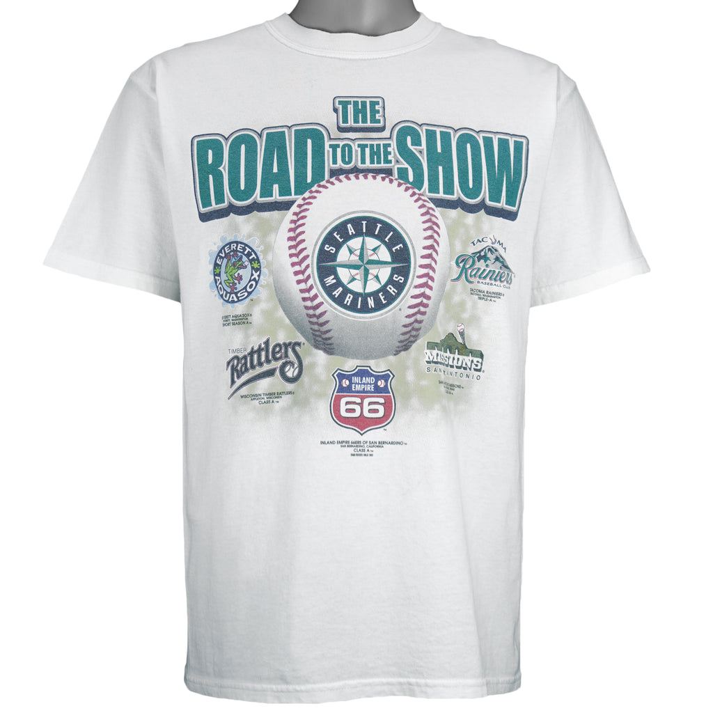 2003 vintage MLB Seattle Mariners "Road to the Show" spell-out T-Shirt by Gildan. White in color with farm team logos (Everett Aquasox, Wisconsin Timber Rattlers, Inland Empire 66ers of San Bernardino, San Antonio Missions, Tacoma Rainiers), Medium in size and is in excellent condition.