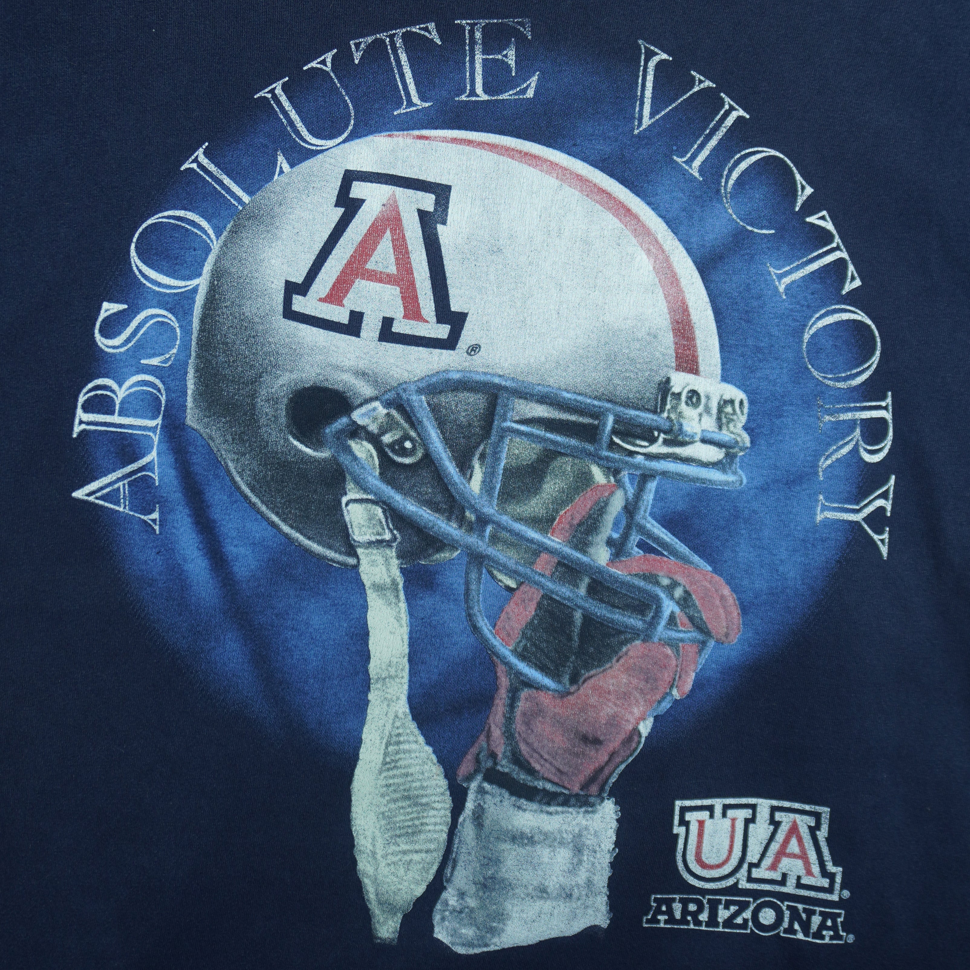 2000s vintage NCAA University of Arizona Wildcats football helmet T-Shirt. Dark blue in color with "Absolute Victory" spell-out on front and "We Came, We Saw, We Kicked Butt" on back. Fits Medium in size and in excellent condition.