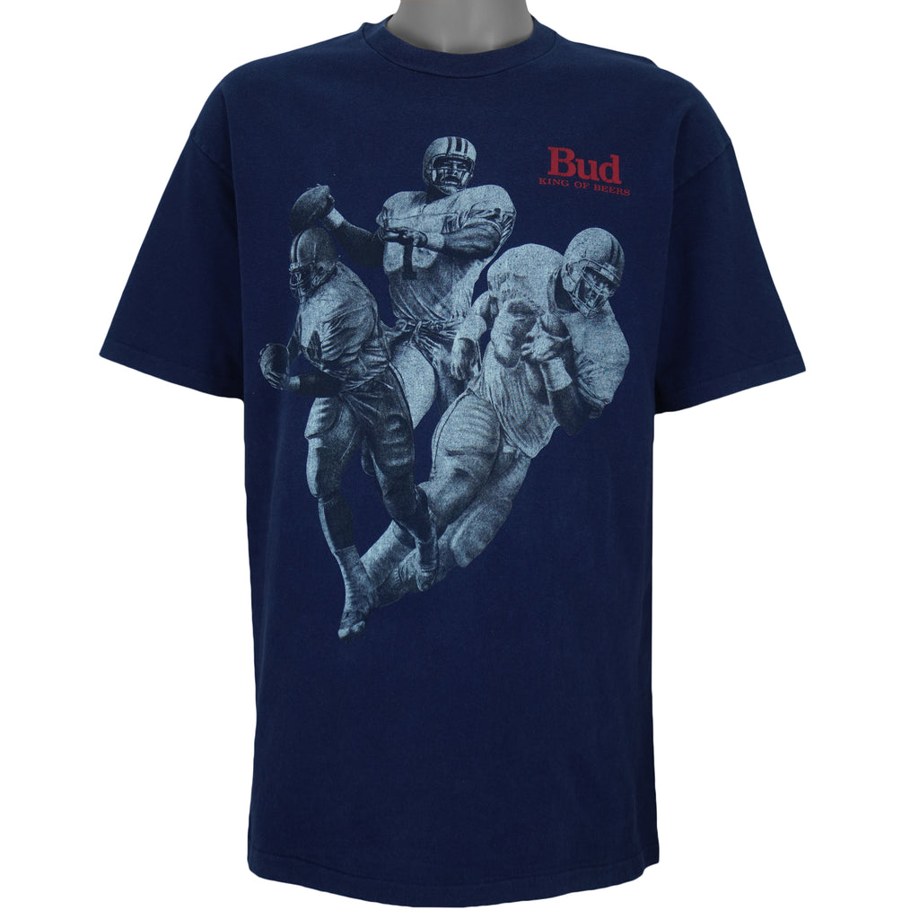 1990s vintage Budweiser single stitch T-Shirt by Hanes Beefy-T. Blue in color with three players and "Bud, King of Beers" small spell-out on front, X-Large in size and is in excellent condition.