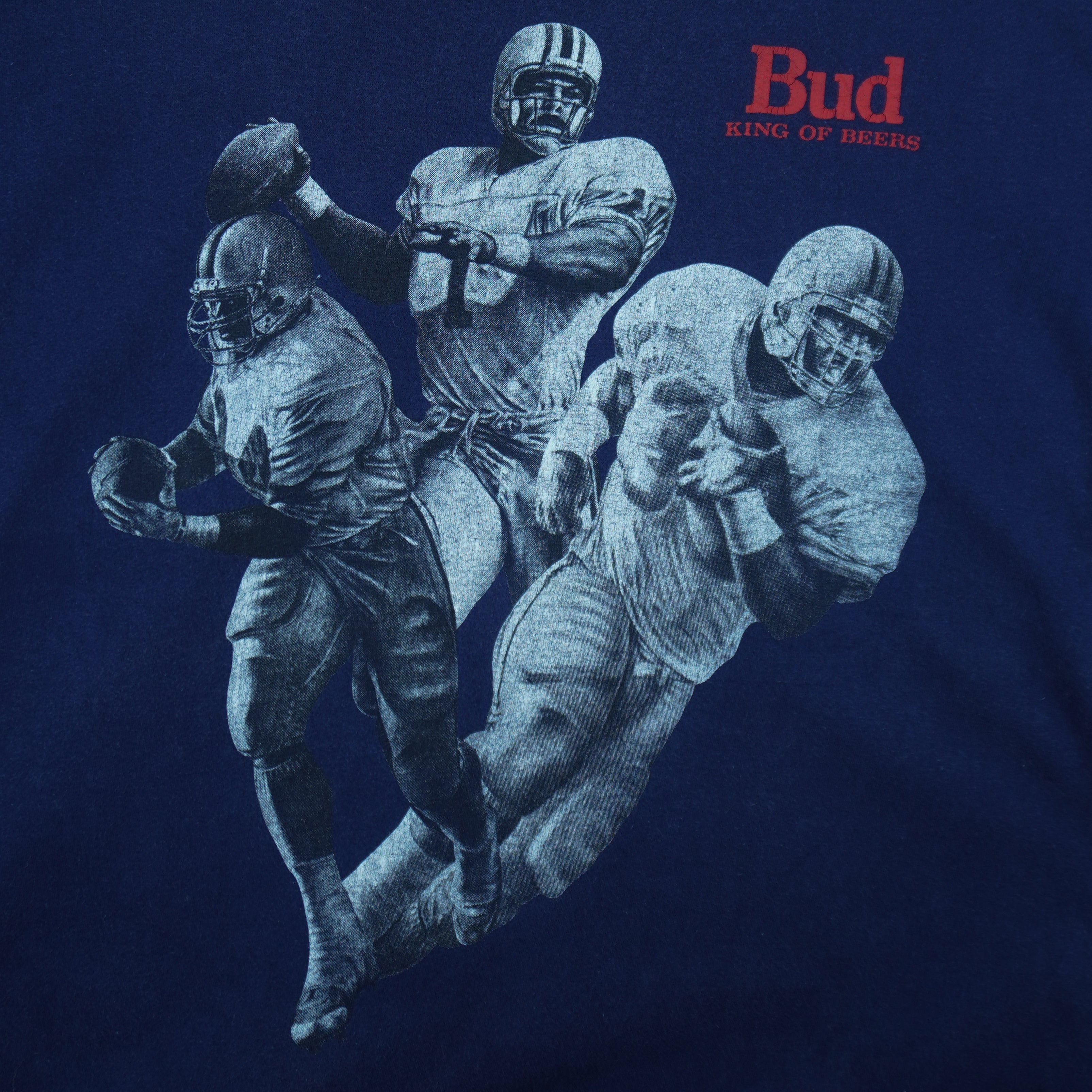 1990s vintage Budweiser single stitch T-Shirt by Hanes Beefy-T. Blue in color with three players and "Bud, King of Beers" small spell-out on front, X-Large in size and is in excellent condition.