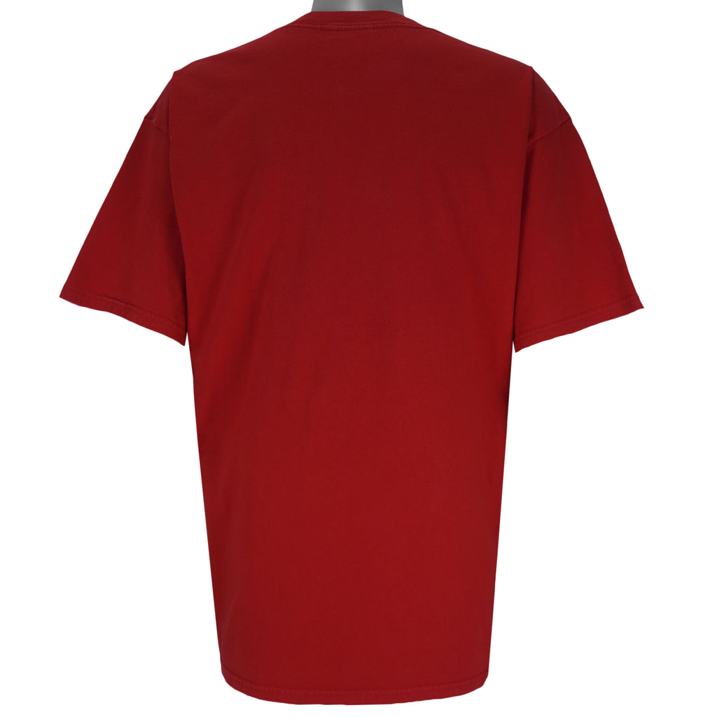 2004 vintage NCAA University of Nebraska-Lincoln Cornhuskers spell-out Gildan T-Shirt. Red in color with "Rise of the Machine, West Coast Offense" text and football player graphic on front by Art-Fx Collectors Edition. X-Large in size and in excellent condition.