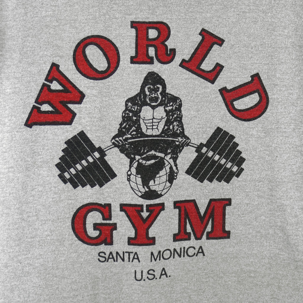 1990s vintage World Gym, Santa Monica USA sleeveless workout shirt. Grey in color with black trim, has a big printed graphic of the gorilla logo on front and back, fits Medium in size, and is in excellent condition.