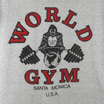 1990s vintage World Gym, Santa Monica USA sleeveless workout shirt. Grey in color with black trim, has a big printed graphic of the gorilla logo on front and back, fits Medium in size, and is in excellent condition.