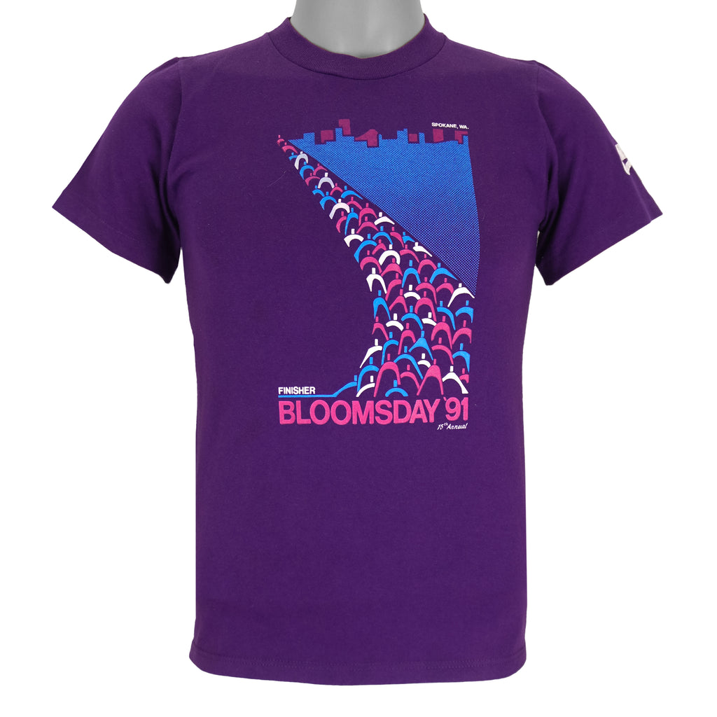 1991 vintage Bloomsday, Spokane Washington, Finisher T-Shirt by Jerzees. Purple in color with abstract people and skyline graphic printed on front and Nike insignia on left sleeve, tagged size Small and is in excellent condition.