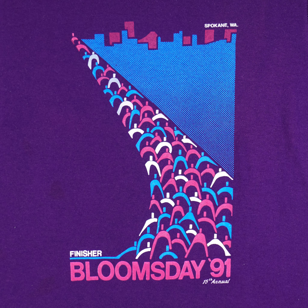1991 vintage Bloomsday, Spokane Washington, Finisher T-Shirt by Jerzees. Purple in color with abstract people and skyline graphic printed on front and Nike insignia on left sleeve, tagged size Small and is in excellent condition.