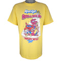A vintage yellow Kool-Aid Rock-A-Dile Red Whacky Wild Tour t-shirt with a graphic print of Kool-Aid Man and a dinosaur.
