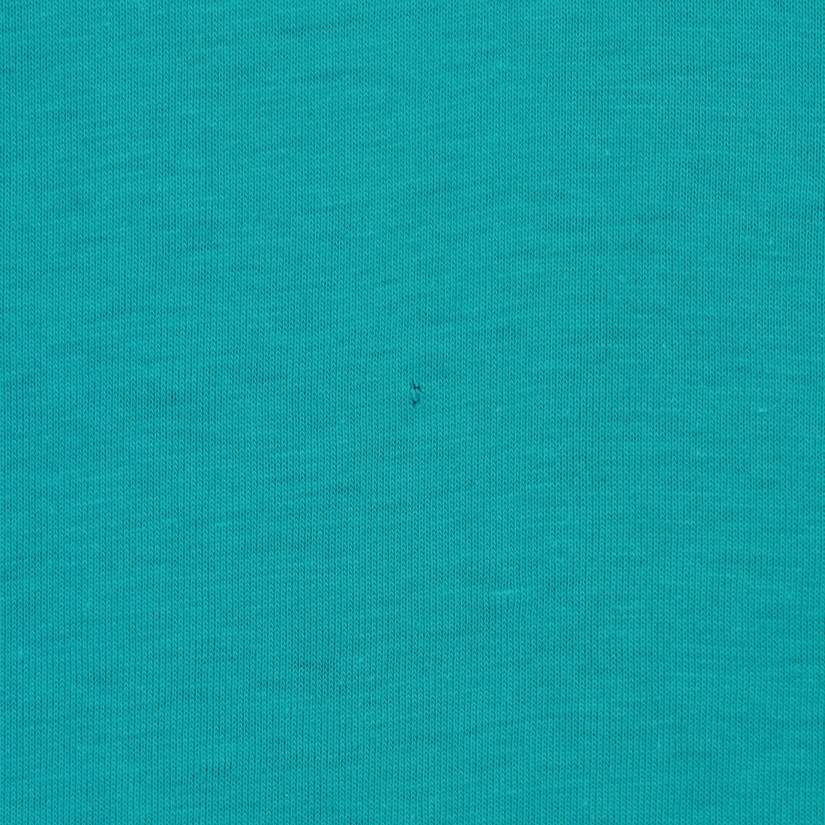 Small dark mark on the teal-green jersey fabric