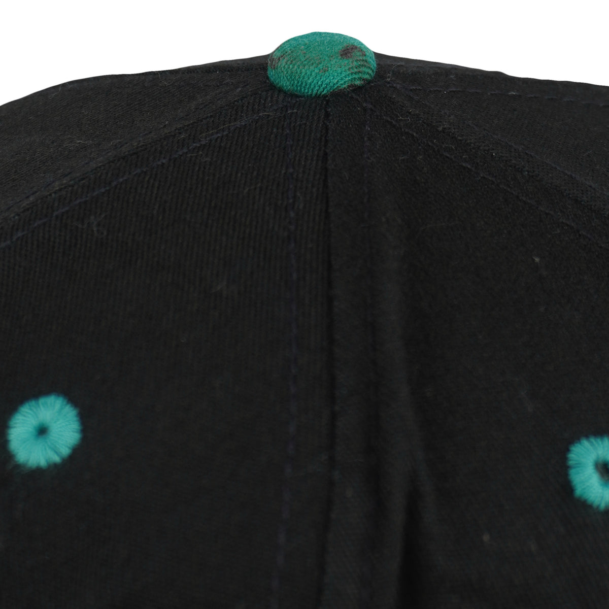 Close view of discoloration on the teal top button of the black Dolphins cap