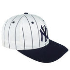 Angled Yankees cap showing white pinstriped panels, navy brim and embroidered NY logo