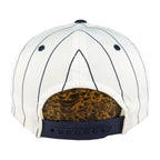 Rear of the white New York Yankees cap with navy stripes, navy eyelets, and a dark plastic snap