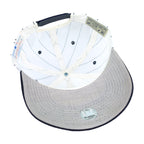 Interior of the white New York Yankees cap with navy stripes, gray underside of brim, and two inner labels