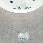 Gray underbrim stitching and round sticker on the white Yankees pinstripe cap