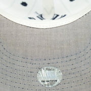 Gray underbrim stitching and round sticker on the white Yankees pinstripe cap