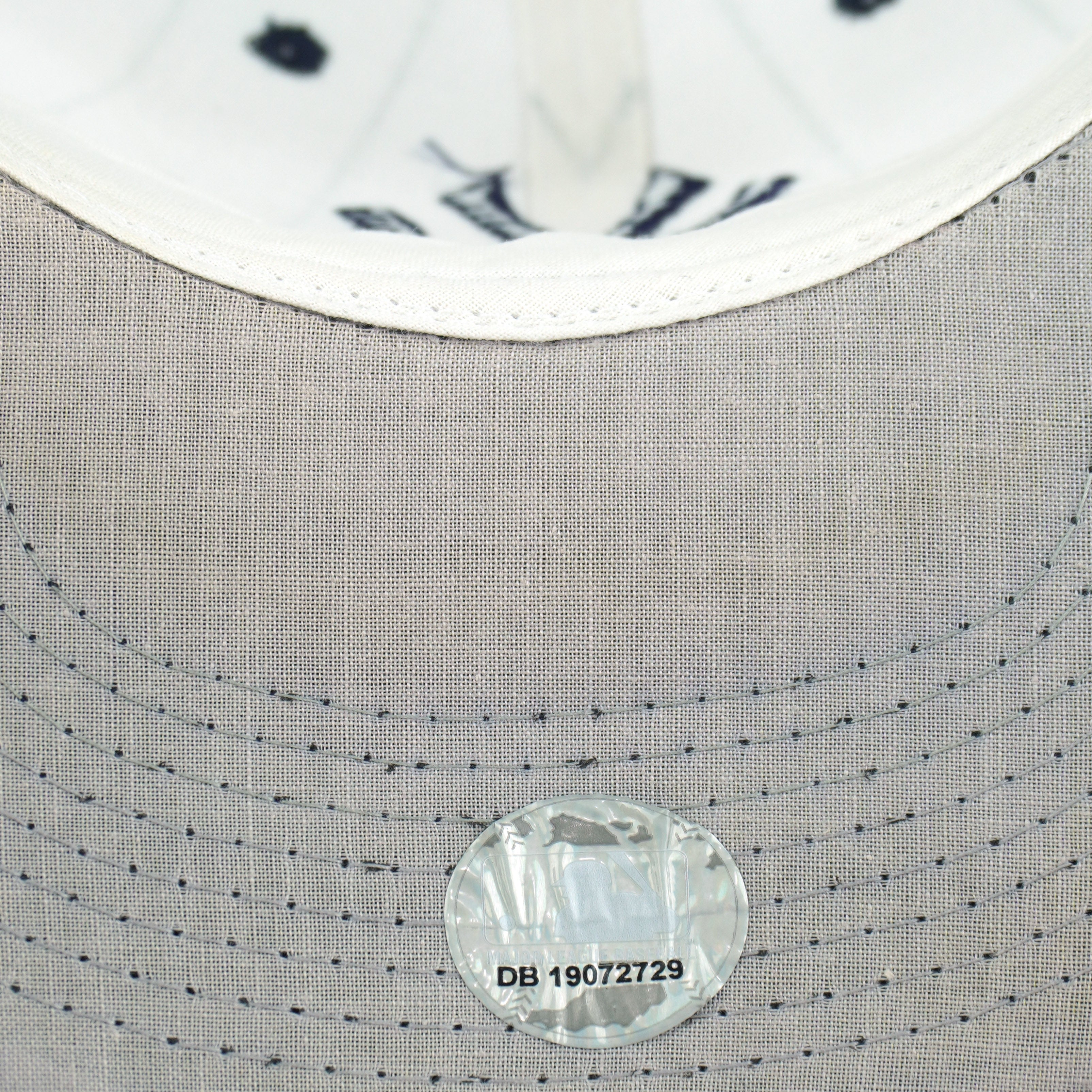 Gray underbrim stitching and round sticker on the white Yankees pinstripe cap