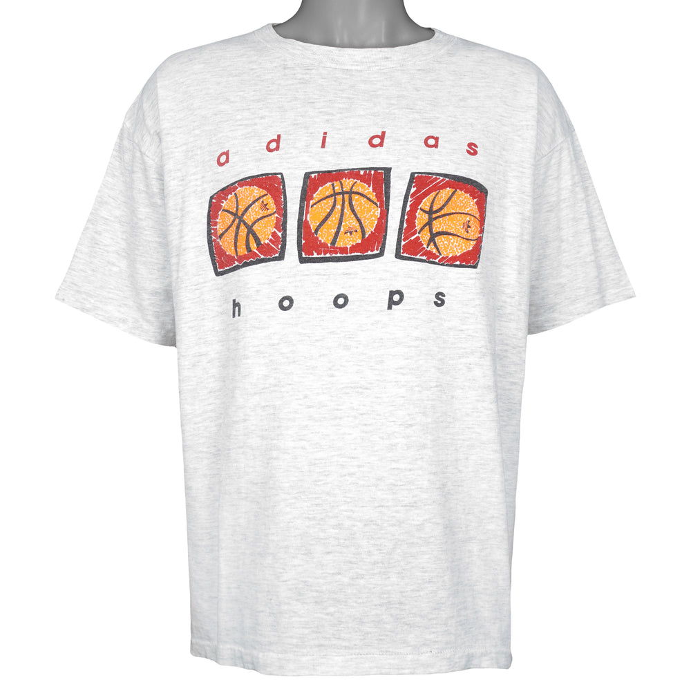 Full front view of the gray Adidas Hoops T-shirt with three orange basketball graphics over red block panels