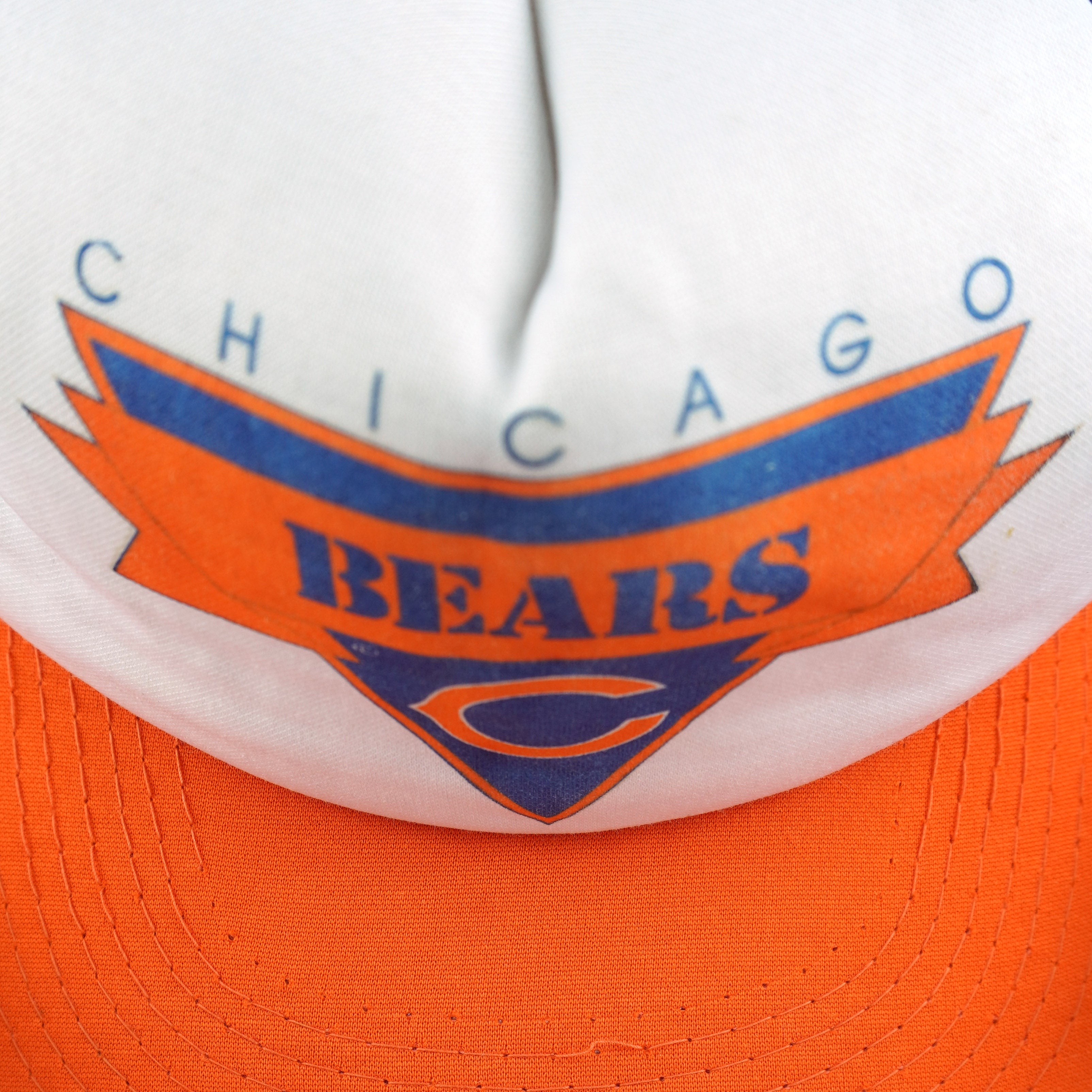 Close view of Chicago Bears lettering and the orange C logo on the white cap front