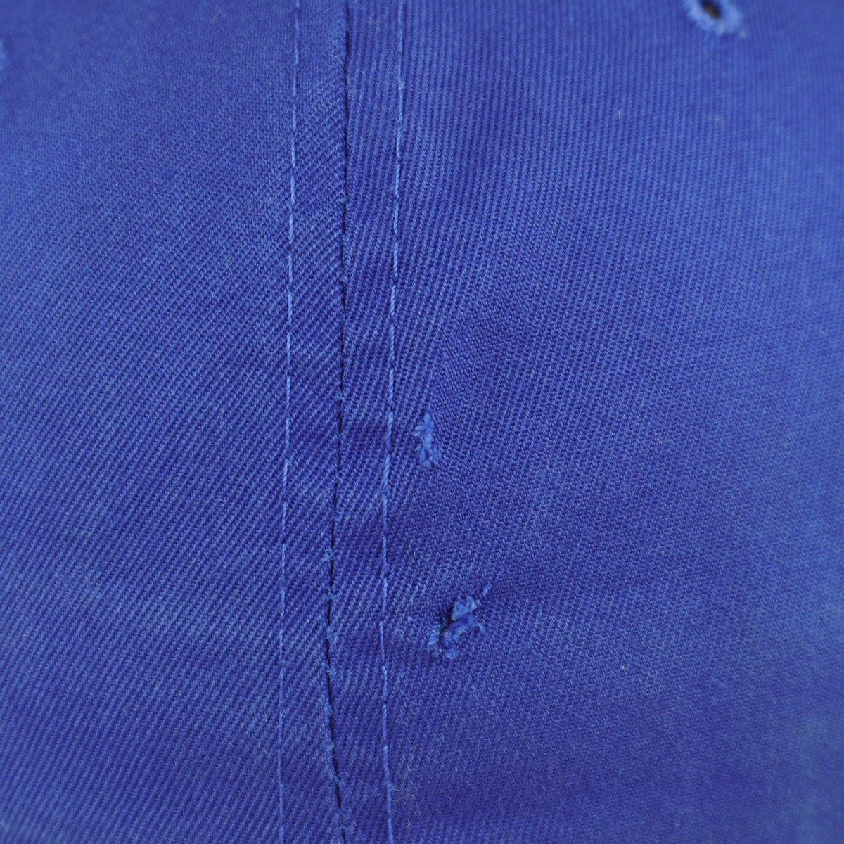 Close view of a small tear in the royal blue crown of the Pistons cap