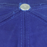 Close view of fraying and surface fading around the blue top button on the Pistons cap
