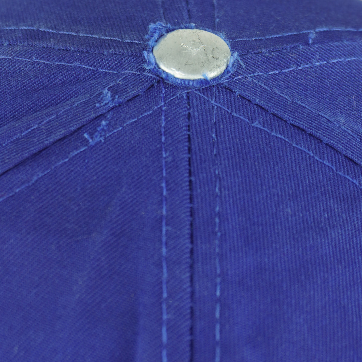 Close view of fraying and surface fading around the blue top button on the Pistons cap