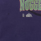 Close-up of dark marks and small holes below the Denver Nuggets logo