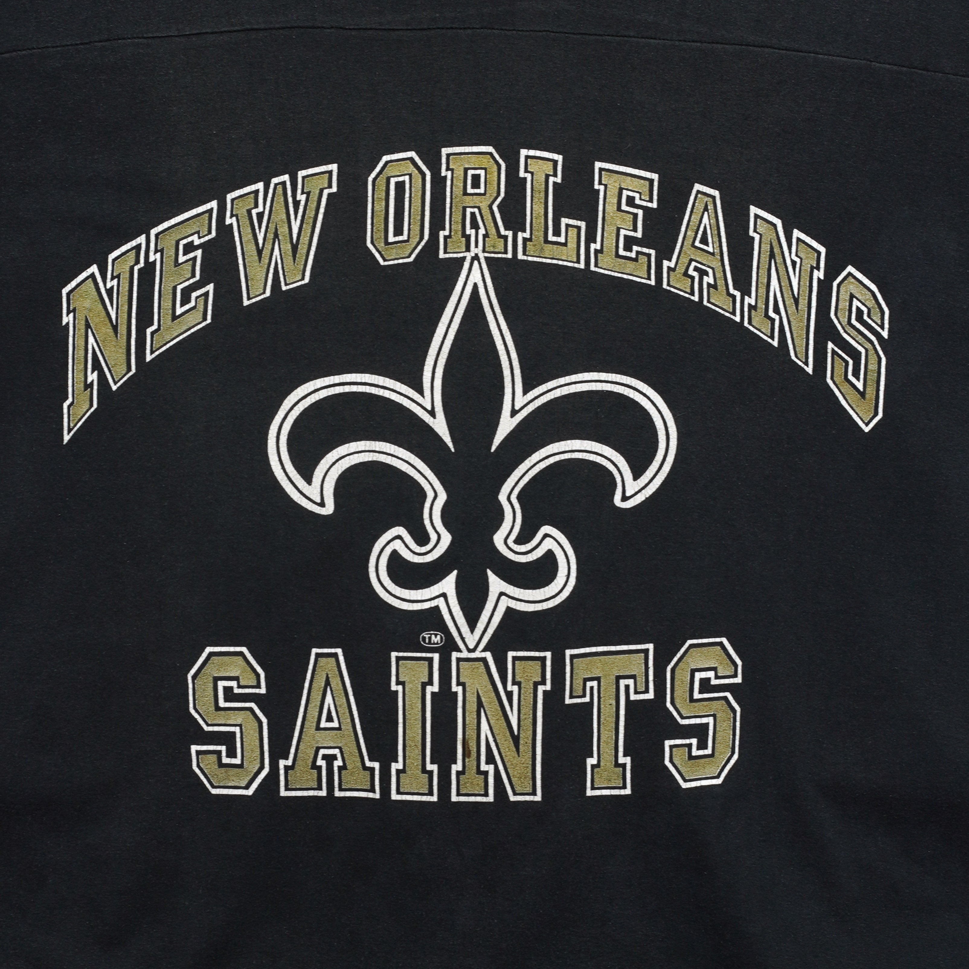 Close-up of the New Orleans Saints wordmark and fleur-de-lis print on the black 1990s V-neck T-shirt.