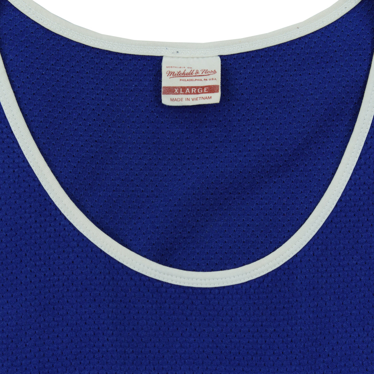 Close-up of the Mitchell & Ness neck label showing size XL inside the blue, white and red 1990s tank top.